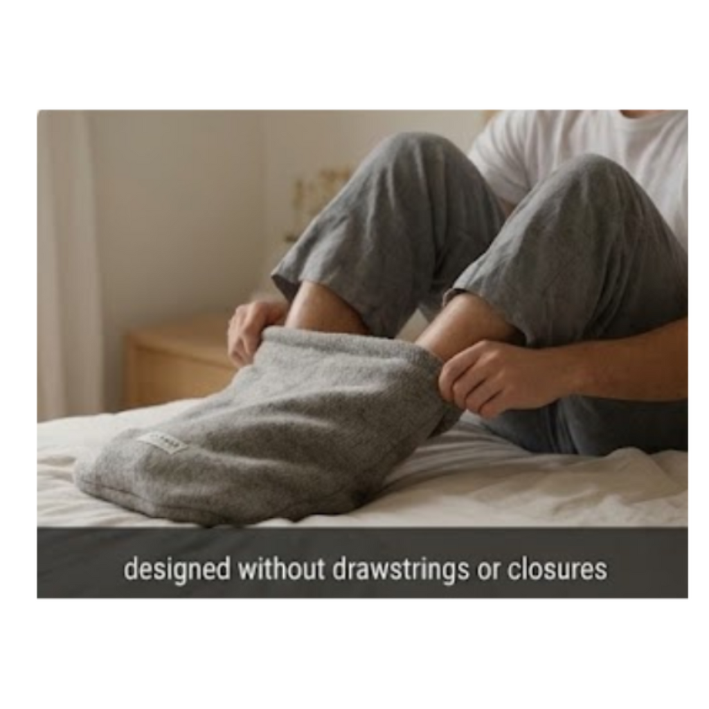 A person sitting on a bed wearing gray pajama pants and a white shirt, with a gray foot pouch. A dark text banner at the bottom reads, 'designed without drawstrings or closures.