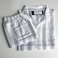 A folded two-piece pajama set with a matching button-front long-sleeve shirt and elastic-waist shorts, both in a white and gray striped pattern, laid flat on a light background. Labelled TED MOON