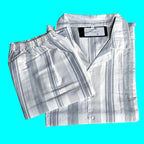 A folded two-piece pajama set with a matching button-front long-sleeve shirt and elastic-waist shorts, both in a white and gray striped pattern, laid flat on a light background. Labelled TED MOON