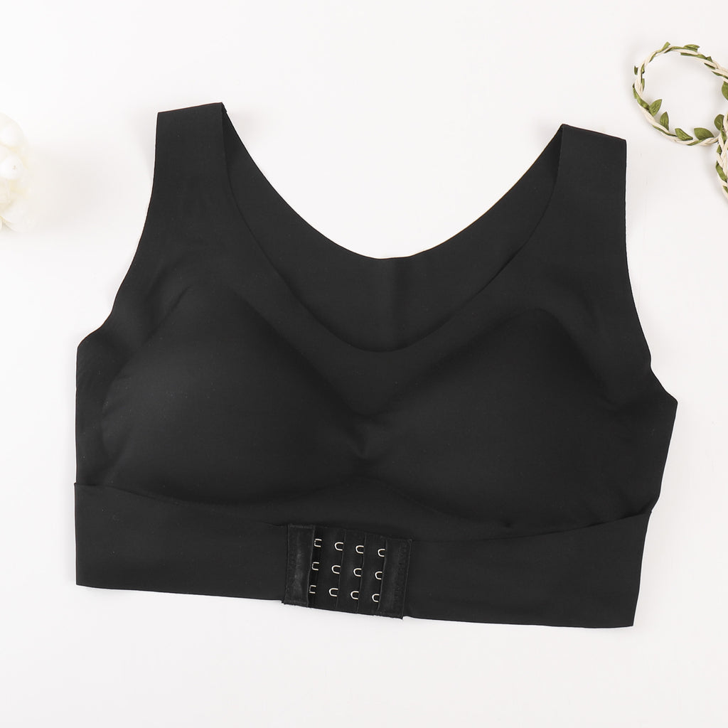 A black wireless bralette with a wide underband and a three-hook closure strap, laid flat on a white background with a decorative leafy vine in the top right corner.